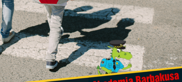 Przejście przez ulicę, nogi rodzica i dziecka na pasach, w prawym dolnym rogu napis "Akademia Barbakusa" i graficznie przedstawiony smok w mundurze strażnika miejskiego