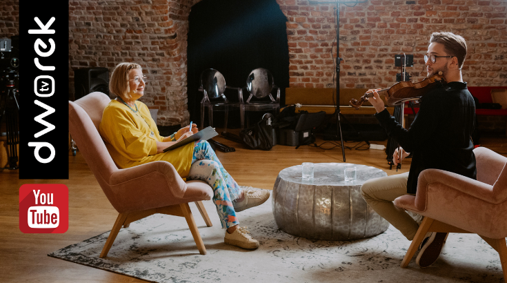Renata Głowacka i Przemysław Prucnal w studio nagrań Dworek TV, siedzą na fotelach przy niskim stoliku kawowym rozmawiając, w tle ceglana ściana