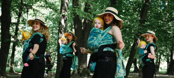 Cztery kobiety z niemowlakami w chustach tańczą w lesie