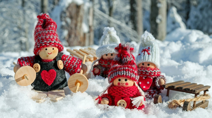 Rodzina zabawek w wełnianych czapkach siedzi, uśmiechnięta na śniegu.