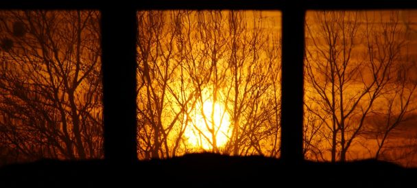 widok przez okno na zachodzące słońce