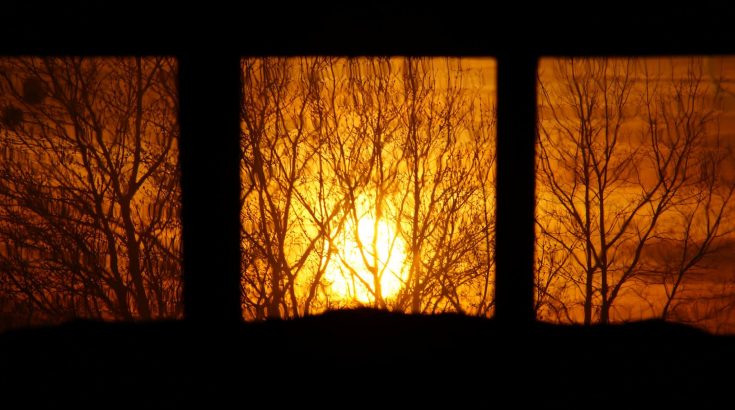 widok przez okno na zachodzące słońce