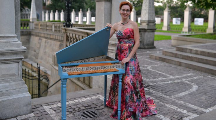Paulina Tkaczyk-Cichoń - artystka w kolorowej długiej sukni stoi obok klawesynu.