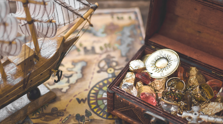 Otwarta drewniana skrzynia pełna błyszczących klejnotów.