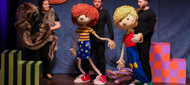 Na zdjęciu troje aktorów z lalkami wielkości dorosłego człowieka - chłopcem z blond włosami, chłopcem z rudymi włosami i wielkim wężem.