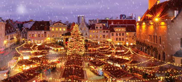 Oświetlone miasto wieczorową porą, na środku oświetlona choinka.