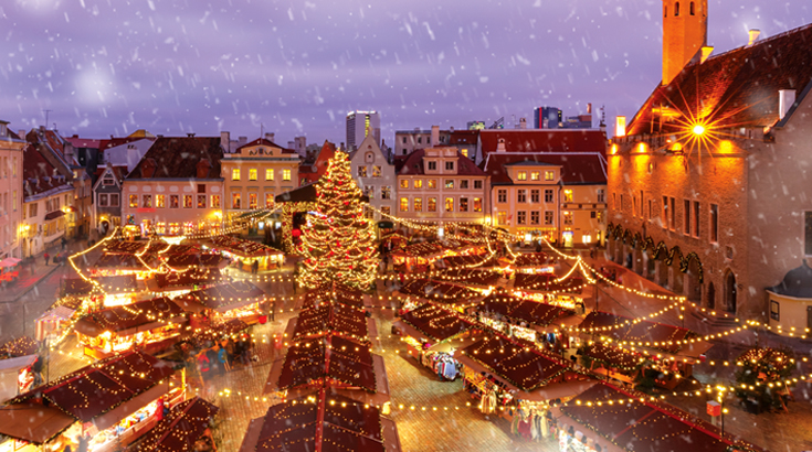 Oświetlone miasto wieczorową porą, na środku oświetlona choinka.