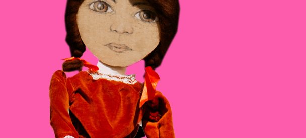 Na różowym tle dziewczynka z czarnymi włosami w warkoczach i czerwonej sukience z założonymi rękoma na piersiach.