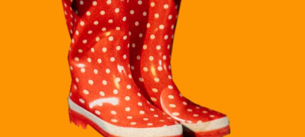 Na ciemnożółtym tle czerwone kalosze w białe kropki