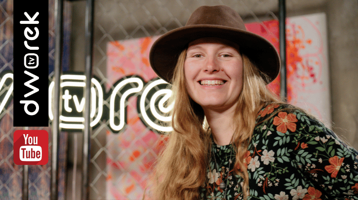 Uśmiechnięta kobieta z blond długimi włosami w kapeluszu na tle neonu dworek tv